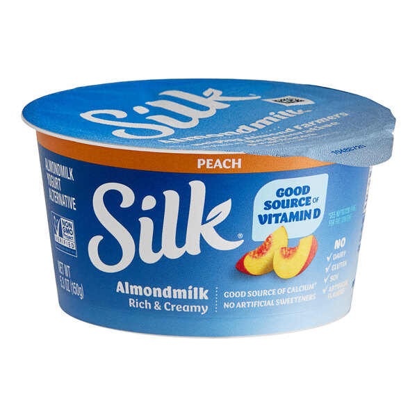 A blue round Silk Dairy-Free peach almond milk yogurt alternative container with a blue lid.