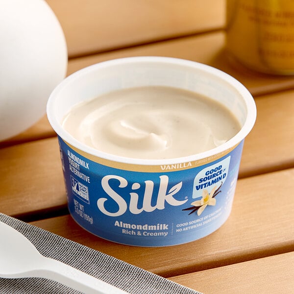 A container of Silk Dairy-Free Vanilla Almond Milk Yogurt on a table.