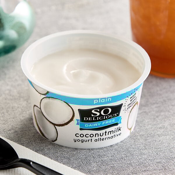 A close-up of a So Delicious Dairy-Free Plain Coconut Milk Yogurt cup with a spoon.