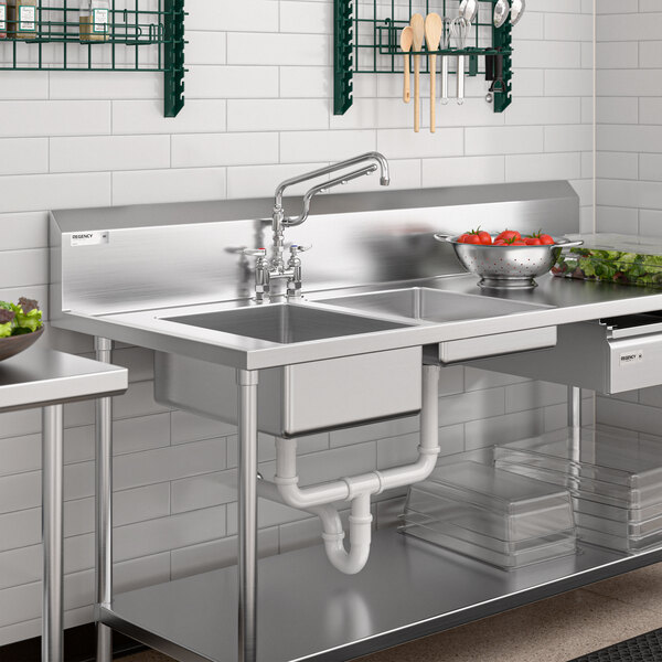 A stainless steel commercial kitchen sink with a deck mount mixing faucet, 12-inch swing nozzle, and 10-inch sprayer arm.