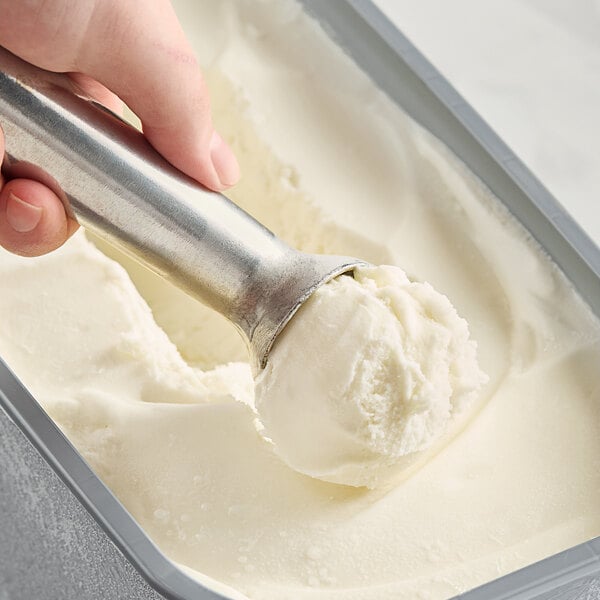 A hand scooping Bravo Gelato Fior di Latte into a metal pan.