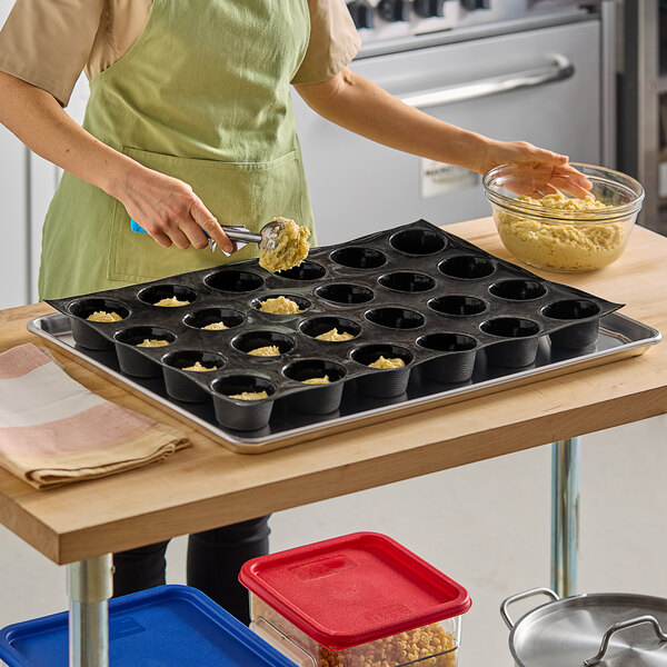 A person using a Sasa Demarle Flexipan Origine muffin mold to make muffins.