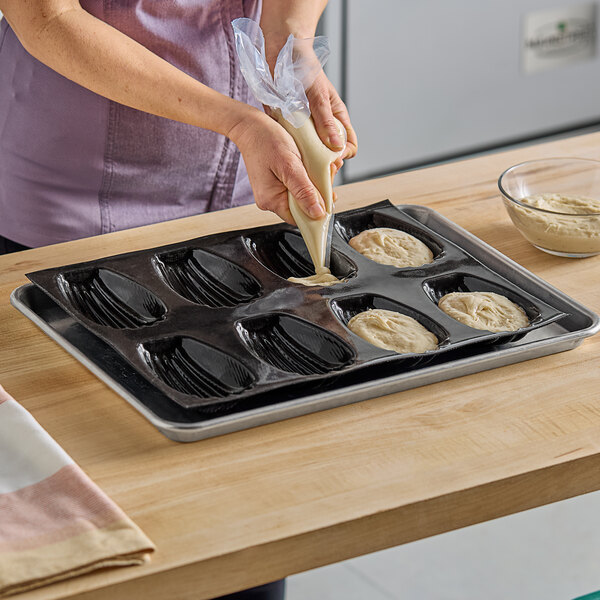 A woman using a Sasa Demarle silicone madeleine mold to put dough into a pan.