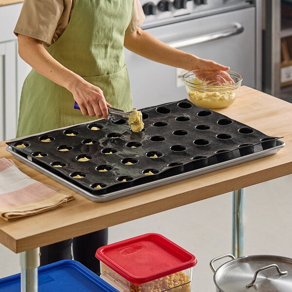 A person in an apron using a Sasa Demarle silicone cylinder mold to make desserts.