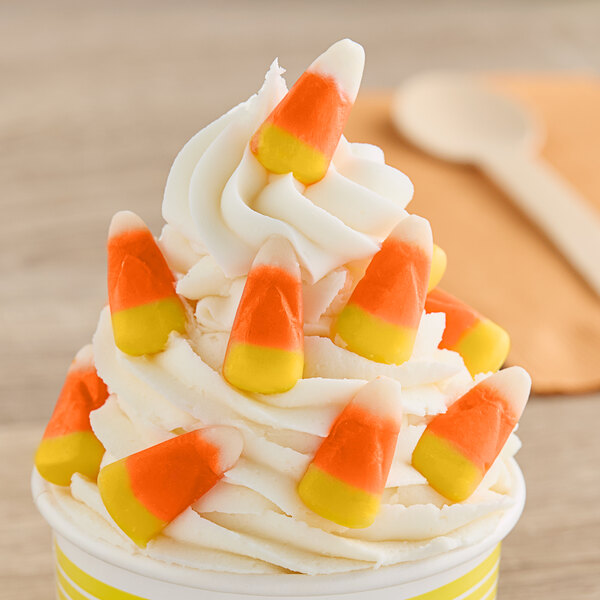 A cup of ice cream with candy corn on top.