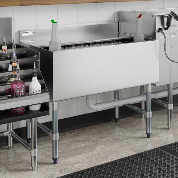 A Regency underbar ice bin with sliding lid and bottle holders filled with ice and bottles on a counter.