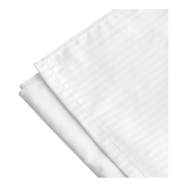 A folded white queen size bed skirt with a tone on tone stripe.