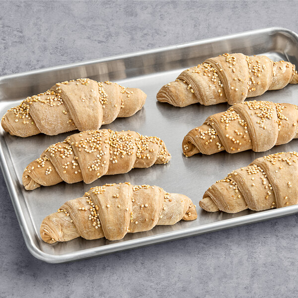 Le Chic Patissier vegan spelt and quinoa croissants with sesame seeds on a baking sheet.
