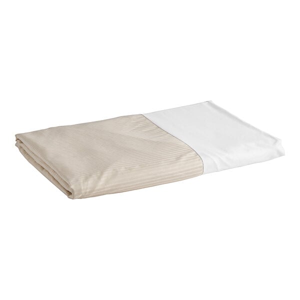 A white bed skirt with tan stripes on a bed.