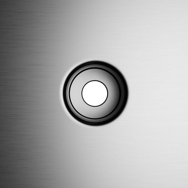 The black and white circular button on a metal surface.