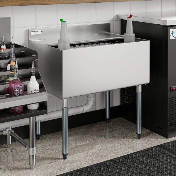 A Regency stainless steel underbar ice bin with sliding lid and bottle holders filled with ice and bottles.