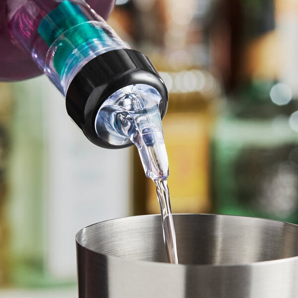 A measured liquor pourer with a collar dispensing liquid into a metal container.