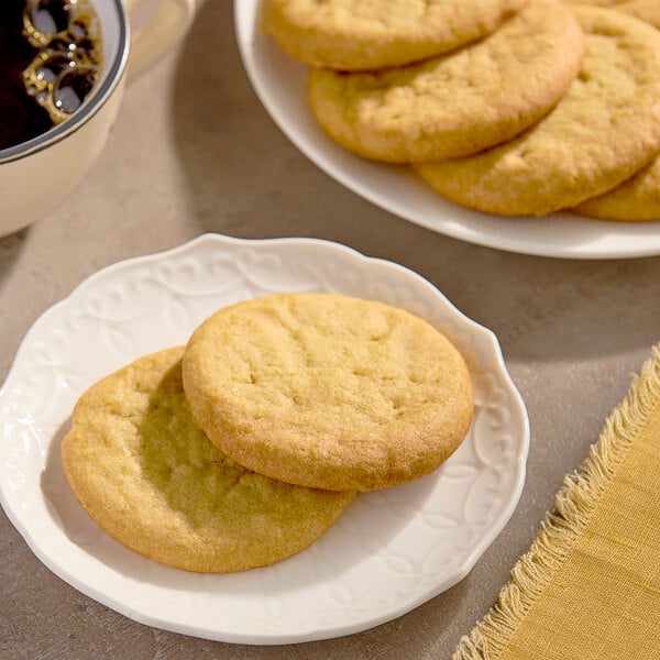 A plate with a stack of Otis Spunkmeyer Lemon Burst cookies next to a cup of coffee.