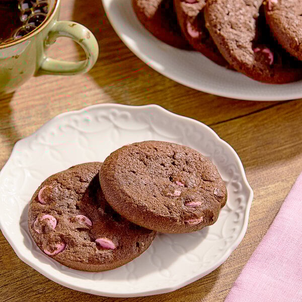 A plate of Otis Spunkmeyer chocolate cookies with pink chocolate candy gems.