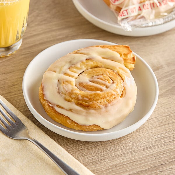An Otis Spunkmeyer Iced Cinnamon Roll on a plate with a fork.