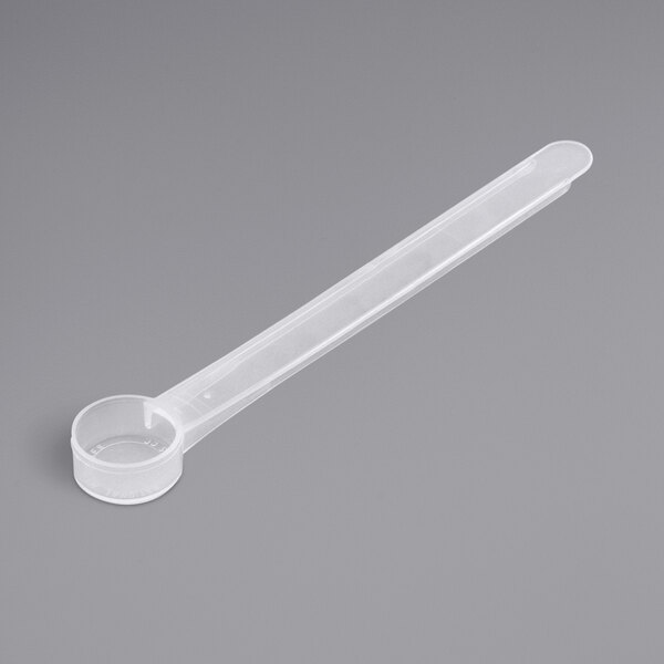 A clear plastic measuring spoon with a long handle.