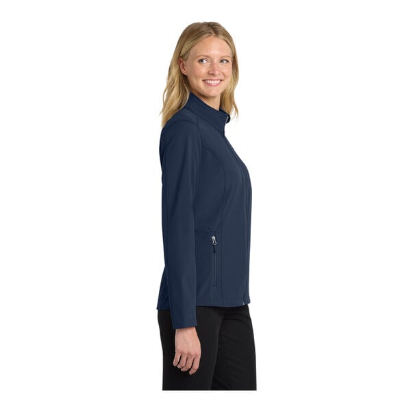 A woman wearing a navy blue Port Authority Core Soft Shell Jacket with black zippers.