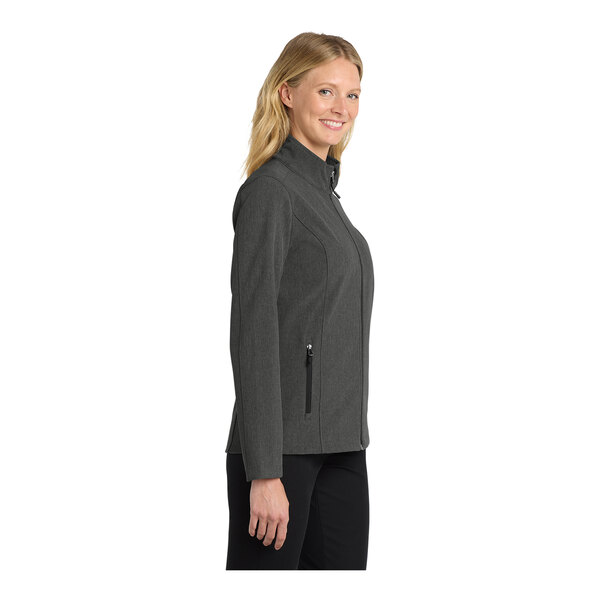 A woman wearing a black and charcoal Port Authority core soft shell jacket.