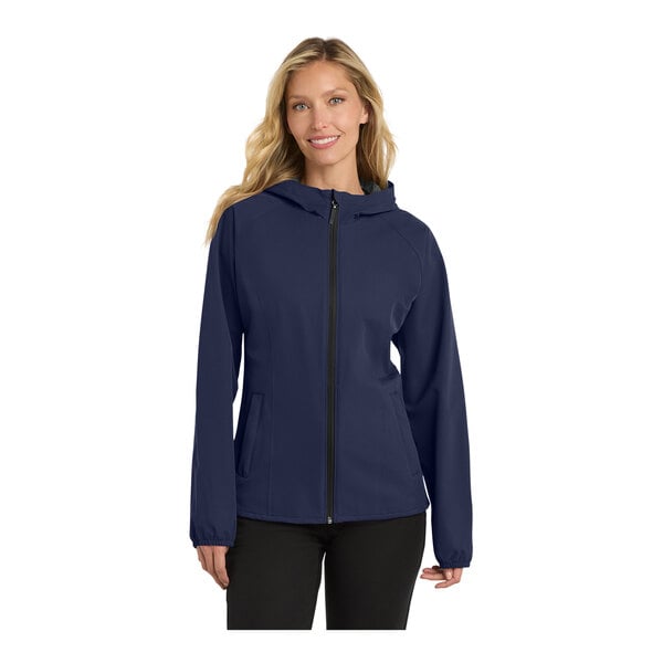 A woman wearing a navy Port Authority rain jacket with a hood and zipper.