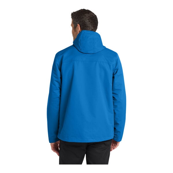 A person wearing a blue Port Authority all-conditions parka jacket.