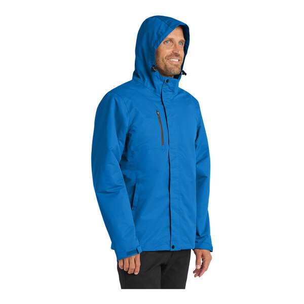 A person wearing a Port Authority Direct Blue All-Conditions Parka jacket.