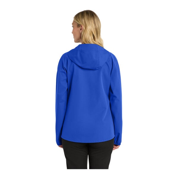 A woman wearing a blue Port Authority rain jacket with a hood.