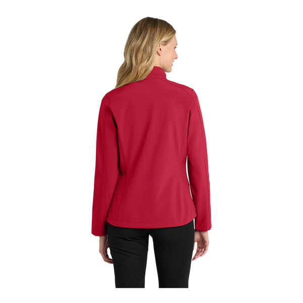 A woman wearing a red Port Authority soft shell jacket.