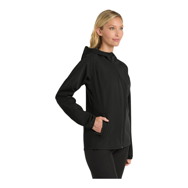A woman wearing a black Port Authority Essential Rain Jacket with a hood.