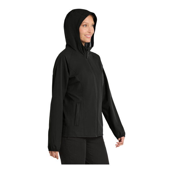 A woman wearing a black Port Authority Essential rain jacket with a hood.