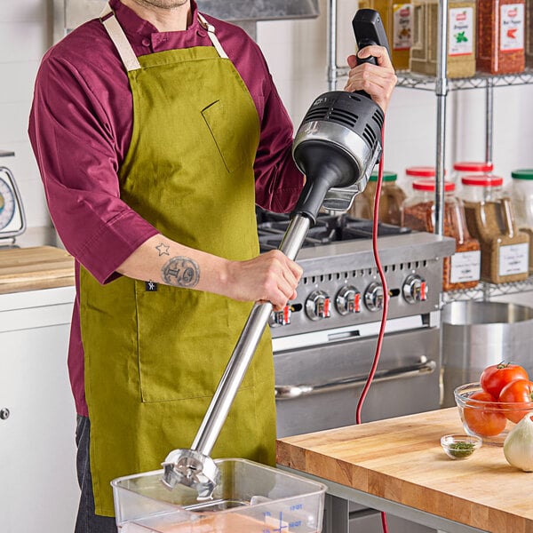 A man using a Vitamix Immersion Blender in a professional kitchen.