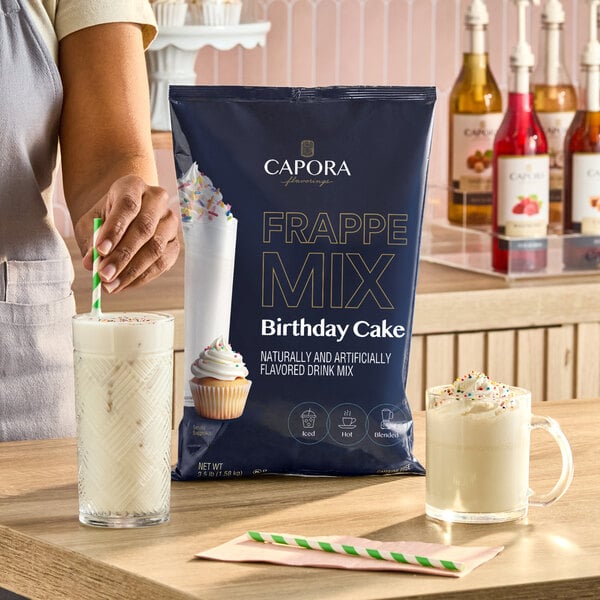 A 3.5 lb. bag of Capora Birthday Cake Frappe Mix displayed on a counter with two prepared birthday cake flavored drinks.