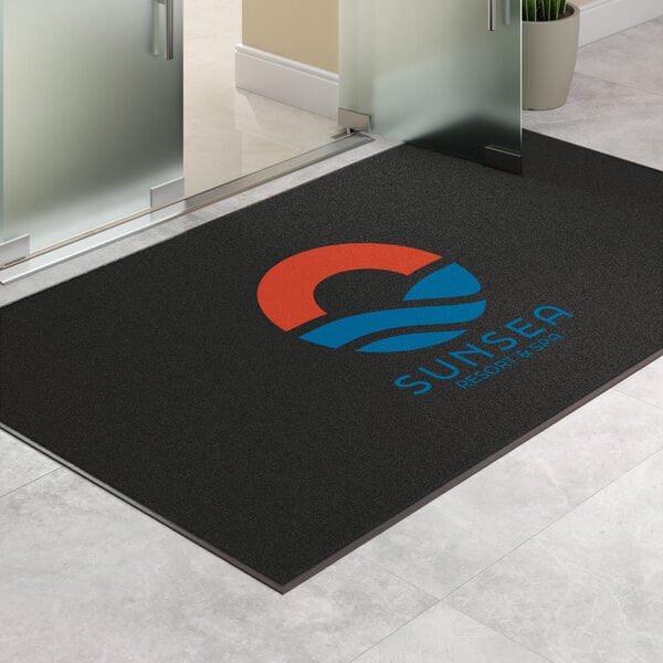 A large rectangular black entrance mat with a colorful logo and text, designed for indoor or outdoor use.