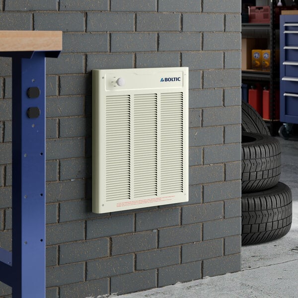 A cream-colored Boltic steel electric fan-forced wall heater mounted on a gray brick wall.