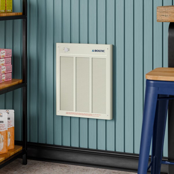 A white Boltic steel electric fan-forced wall heater installed on a blue paneled wall.