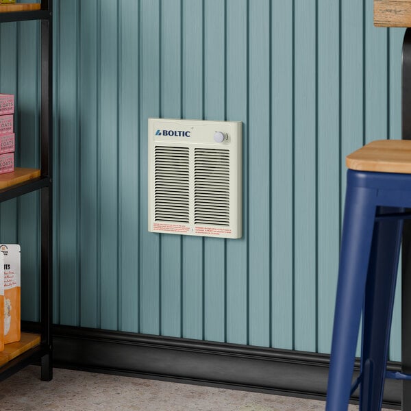 A Boltic steel electric fan-forced wall heater installed on a blue paneled wall.