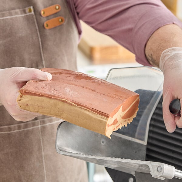 A person cutting a Prime Roots Vegan Hickory Koji-Bacon slab on a counter.