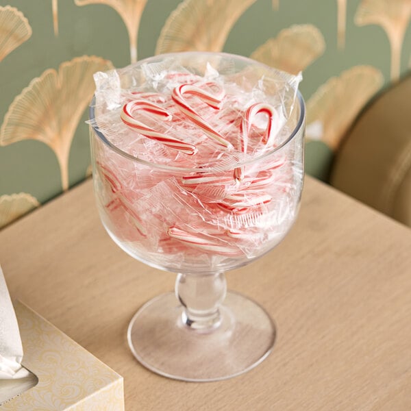 A glass bowl filled with Brach's Mini Candy Canes on a table.