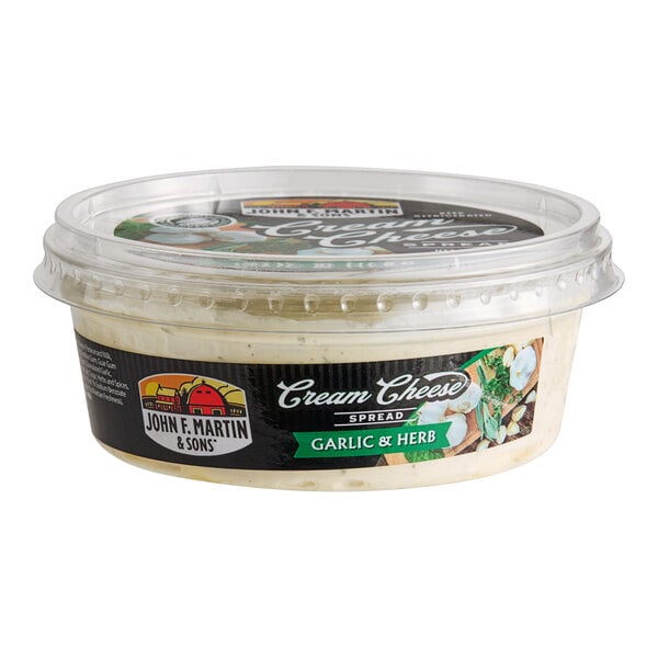 A container of John F. Martin Garlic and Herb Cream Cheese Spread with a label.