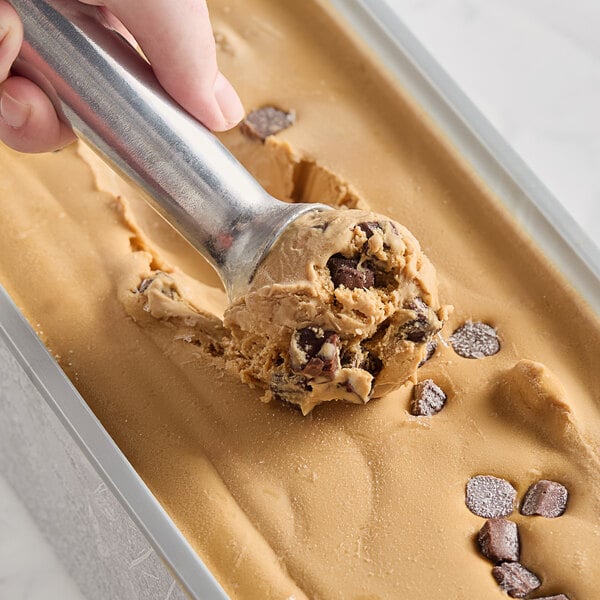 A person scooping Villa Dolce Argentine Salted Dulce de Leche Gelato with Chocolate-Dipped Caramel Truffles