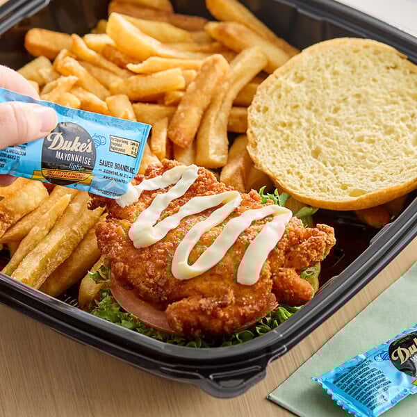 A hand putting Duke's Light Mayonnaise on french fries.