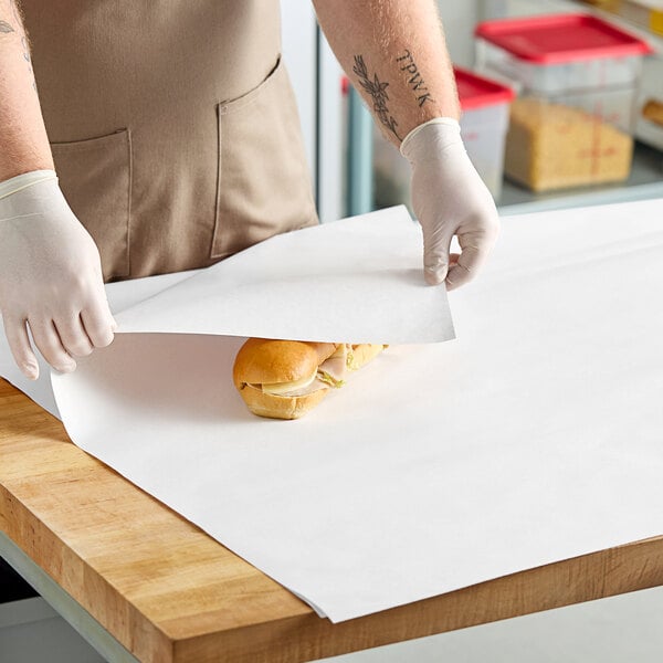 A person wearing gloves puts a sandwich on a Choice newsprint paper.