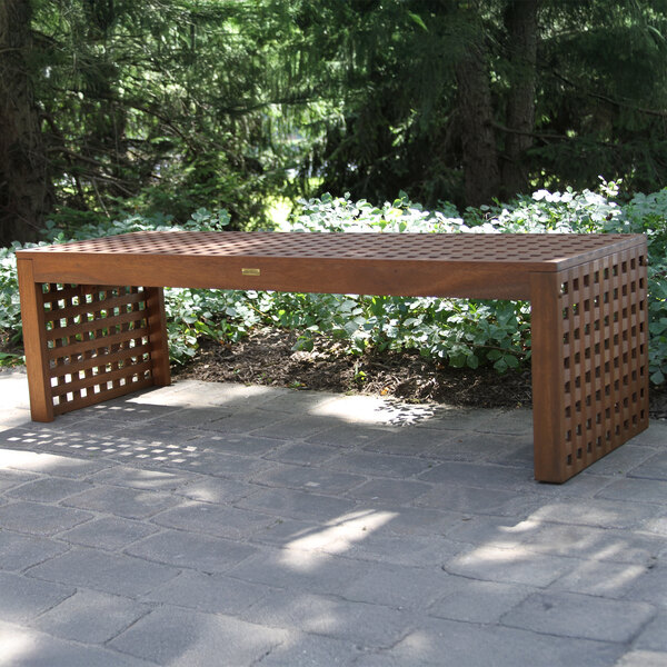 An Outdoor Interiors checkerboard backless eucalyptus bench on a stone surface.