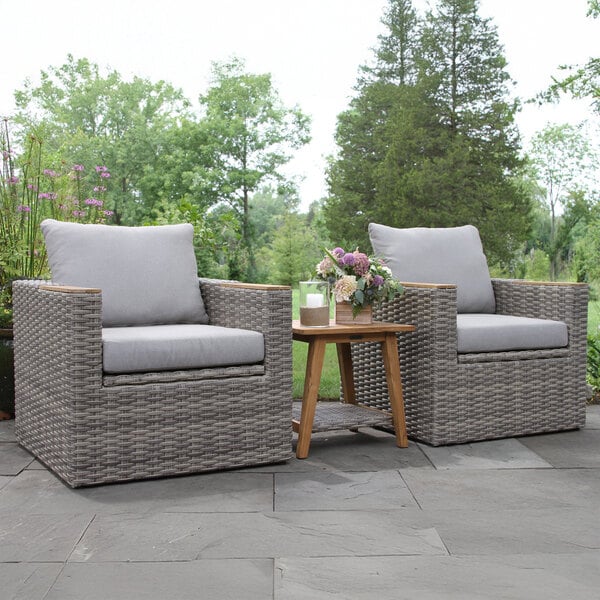 Two Outdoor Interiors teak and wicker captain's chairs on a patio.