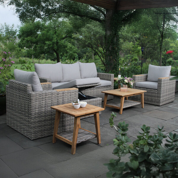 An Outdoor Interiors teak and wicker captain's chair with a storage compartment on a patio.