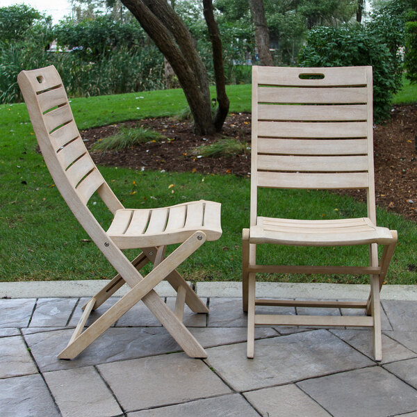 A pair of Outdoor Interiors wooden folding chairs on a stone patio.