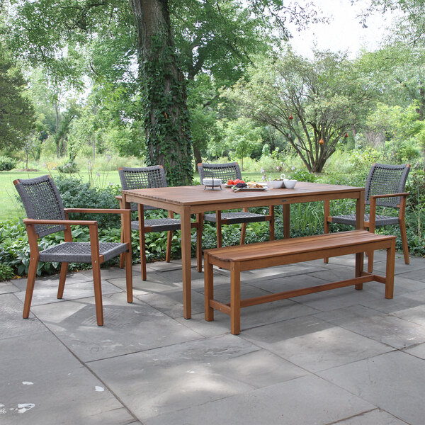 An Outdoor Interiors backless eucalyptus bench on a stone patio.