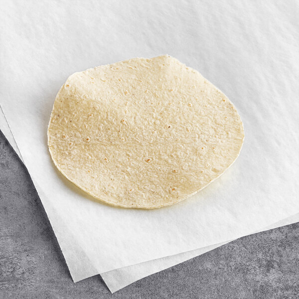A Celia's thin white corn tortilla on a white piece of paper.
