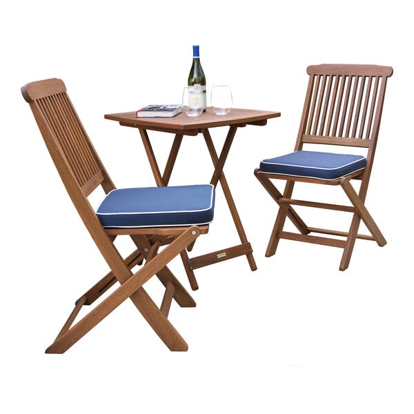 A Square eucalyptus bistro set with blue cushions on a table and chairs with a bottle of wine.