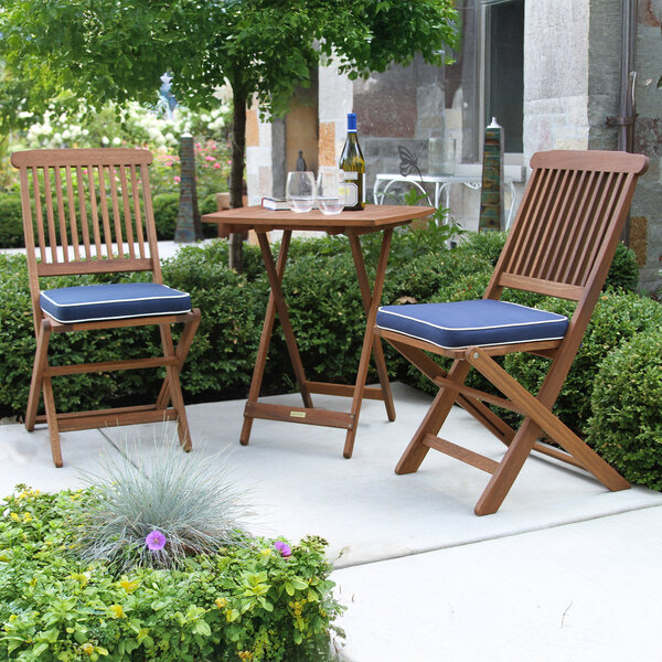 A eucalyptus bistro set with blue cushions on a patio