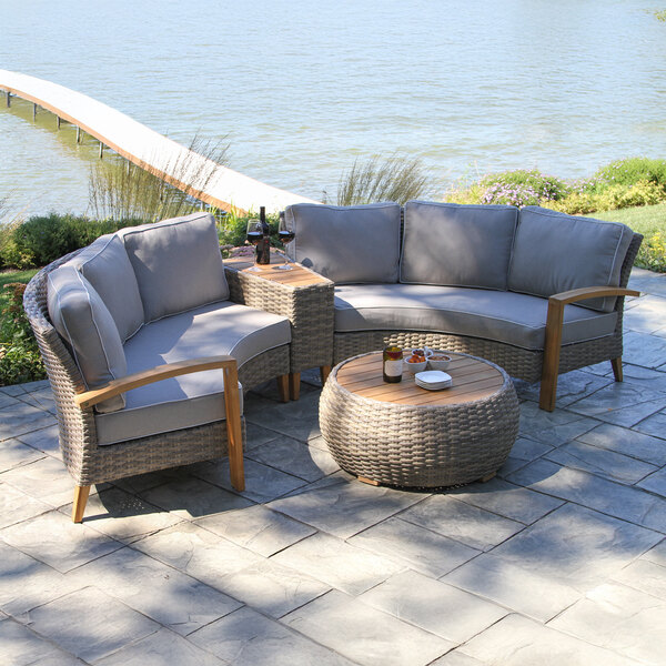A gray wicker couches and table set on a patio.
